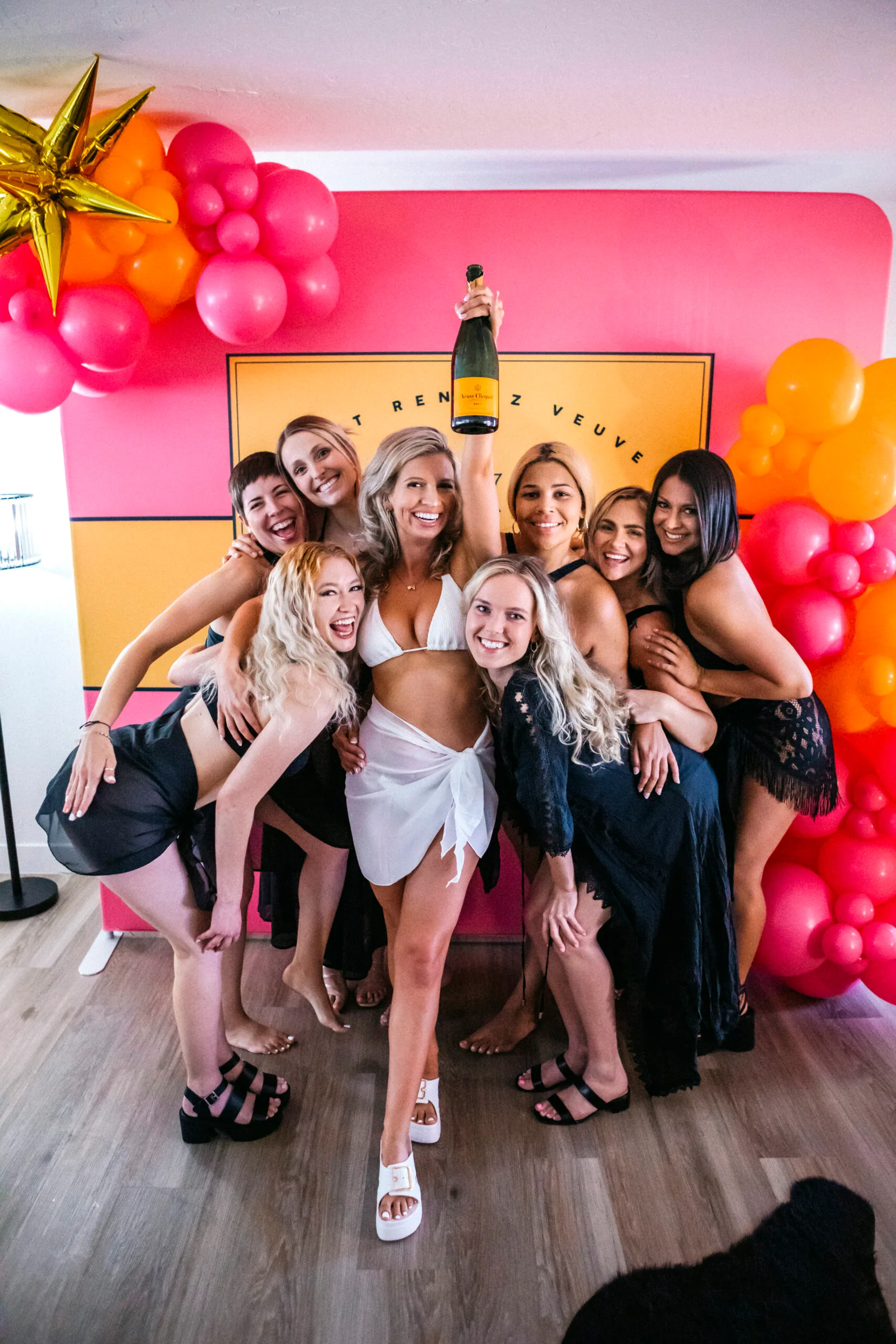 Large bachelorette group in matching outfits posing in front of a vibrant balloon backdrop