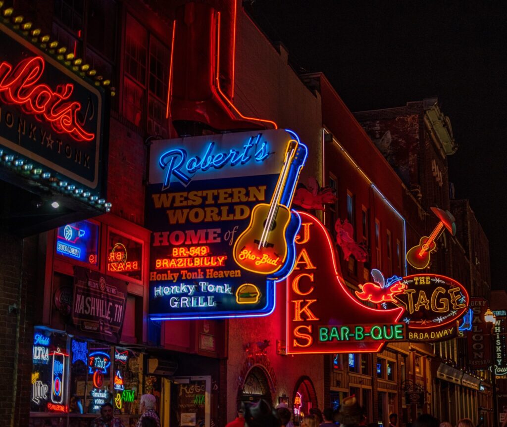 Nashville Broadway strip at night with glowing neon signs and honky-tonk bars