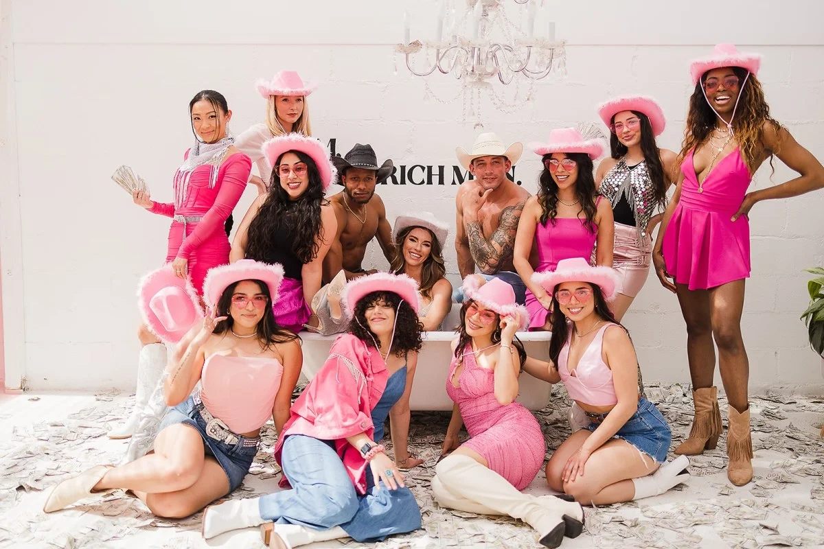 Large bachelorette group in pink outfits seated outdoors at a garden party event