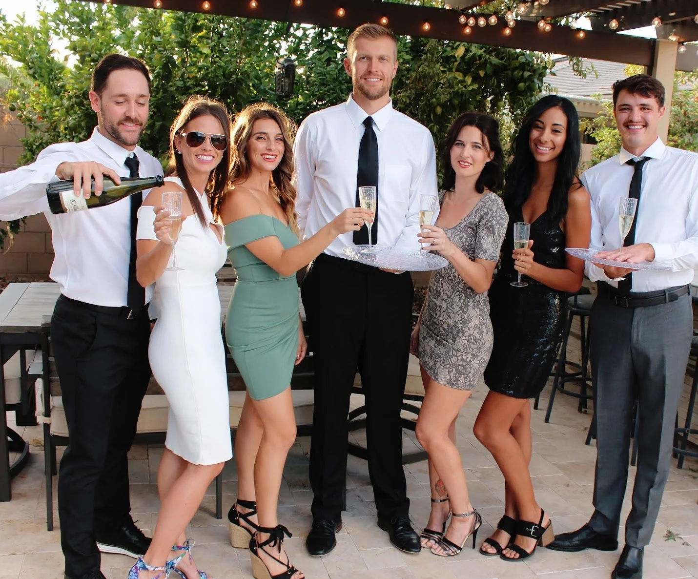 Cocktail Cowboys team in formal attire posing with female guests at an upscale event