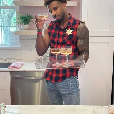 A Cocktail Boys host wearing a sheriff star badge pouring drinks in a kitchen at a bachelorette party
