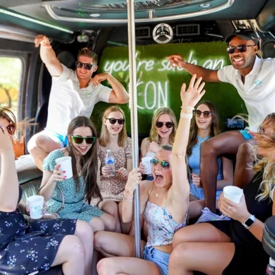A Cabana Boys host and a group of women celebrating inside a decorated party bus with raised hands