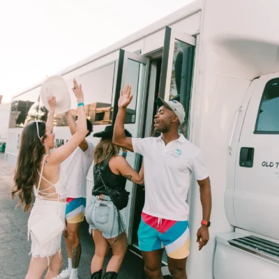 A group of women cheering and celebrating on a party bus with a Cabana Boys host