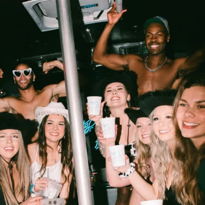 A Cabana Boys host and a large group of women cheering inside a dark decorated party bus