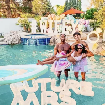 A bachelorette pool party setup with a "Future Mrs." balloon sign and guests celebrating in a backyard pool