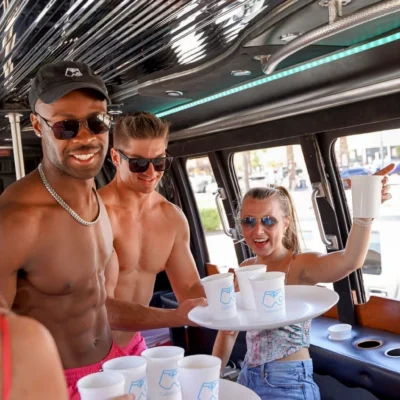 A Cabana Boys host serving drinks to a group of women inside a party bus