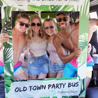 A Cabana Boys host and women posing with an Old Town Party Bus sign inside a decorated bus