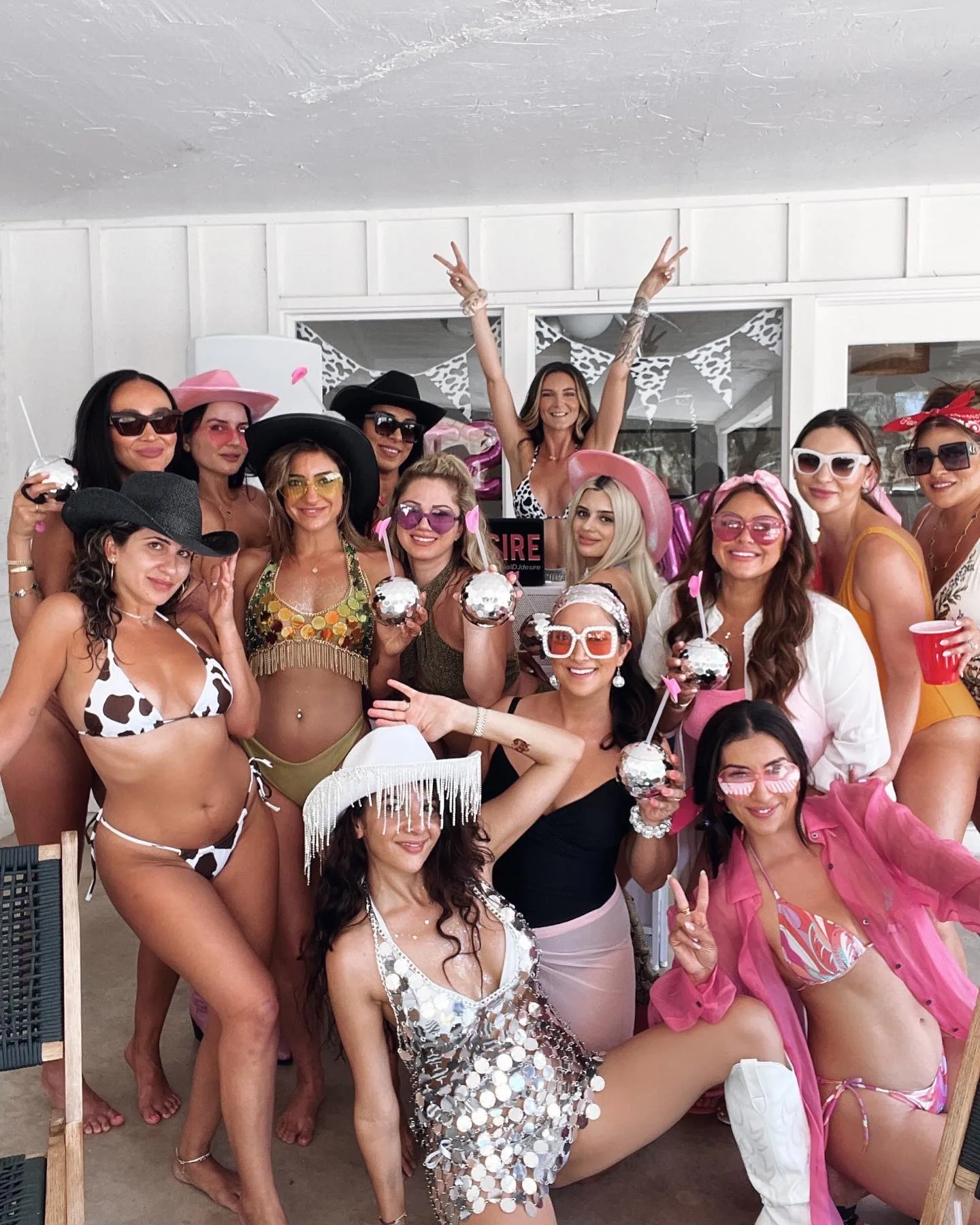 Group of women in colorful bikinis posing together at a lively outdoor pool party
