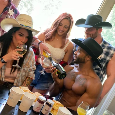 Two Cocktail Cowboys hosts in cowboy hats entertaining a group of women with drinks at an indoor party