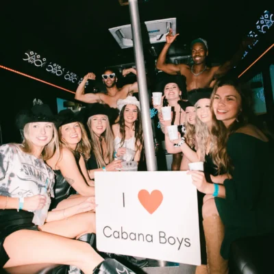 A bachelorette group holding an "I Love Cabana Boys" sign inside a party bus