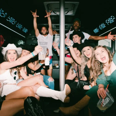A group of women in white holding an "I Love Cabana Boys" sign inside a party bus