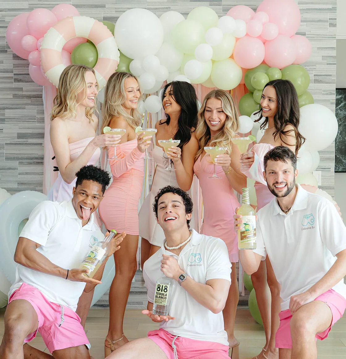 Cabana Boys bartenders and bachelorette party guests holding margaritas in front of a pink and green balloon backdrop.