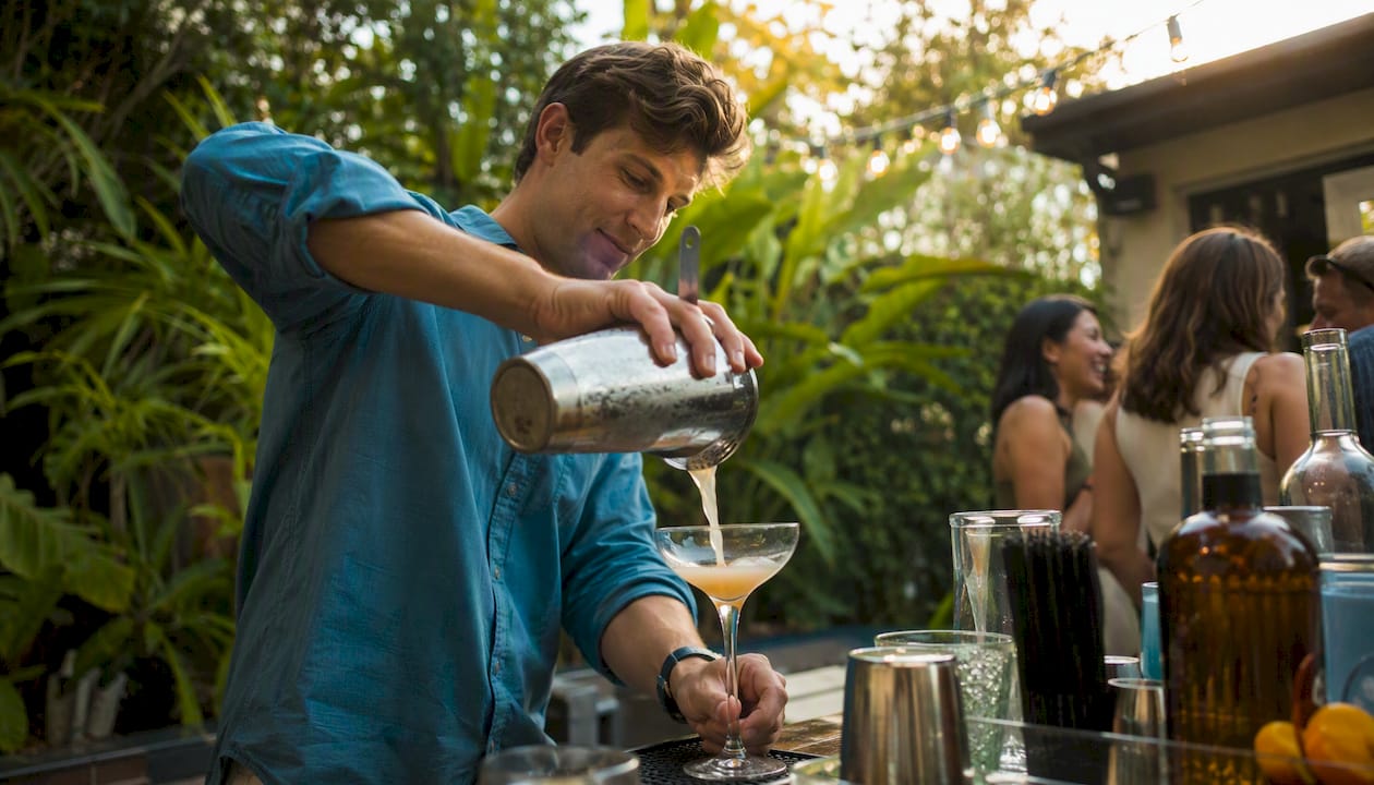 Host pouring cocktails at party bar